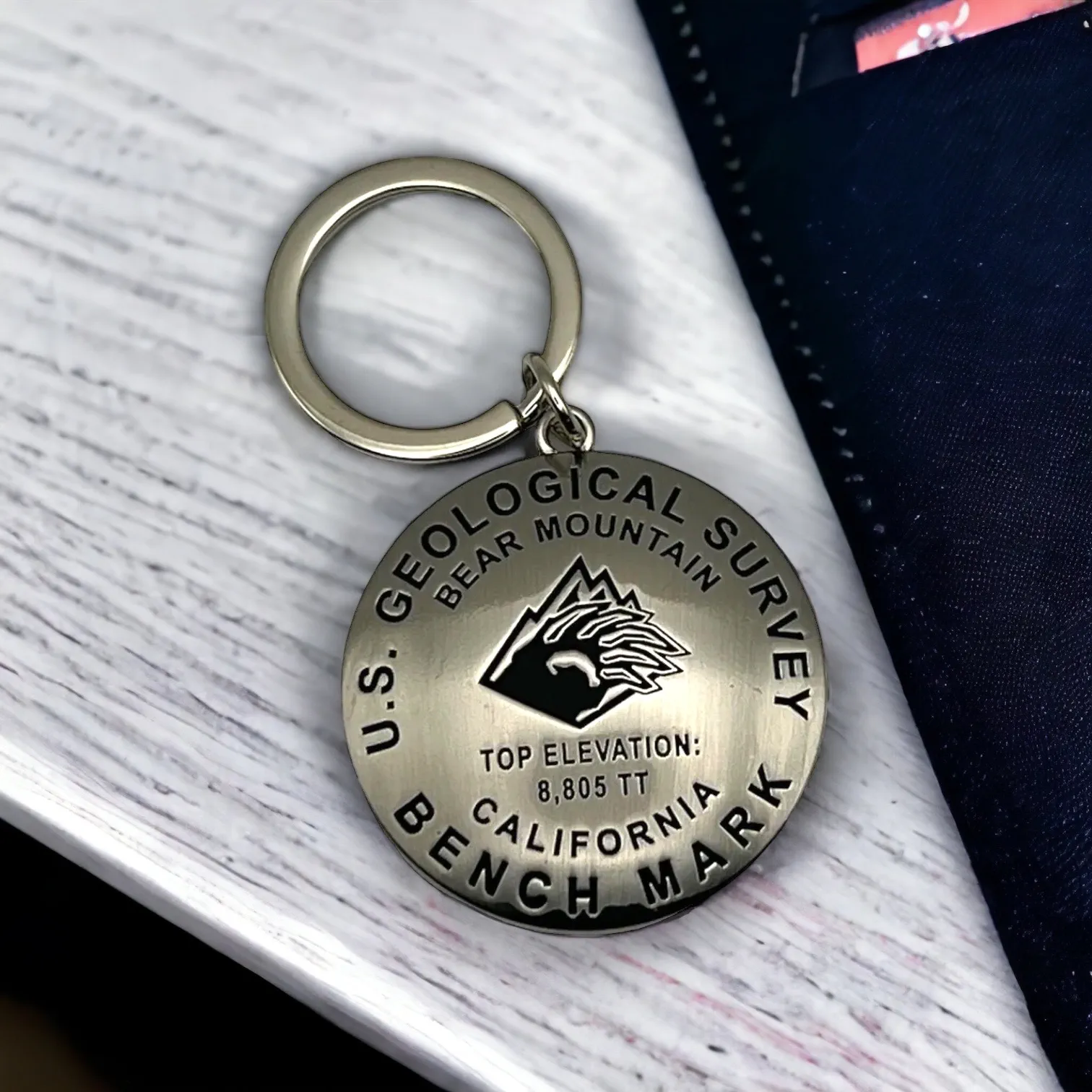 Silver keychange that has a bear mountain logo on it and with Geological Survey Bench Mark/Elevation